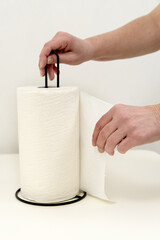 hand holds a paper towel roll on a metal holder
