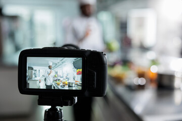Close up camera recording gastronomy expert in restaurant kitchen filming culinary course while cooking delicious dish. Head chef vlogging preparing of gourmet food for gastronomic course on internet.