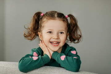 Portrait of a charming little girl with two ponytails, joyful and smiling