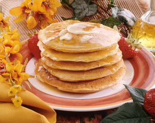 Fresh pancakes with honey and butter on flowers background kitchen table.