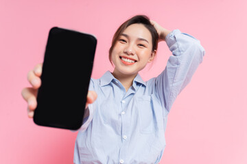 Naklejka premium Image of young Asian girl holding smartphone on pink background