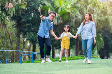 Image of young Asian family playing together at park