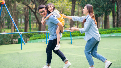 Image of young Asian family playing together at park