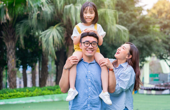 Image of young Asian family playing together at park