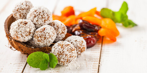 Homemade dietary candies from dates and an apricot in coconut topping. Selective focus. Copy space