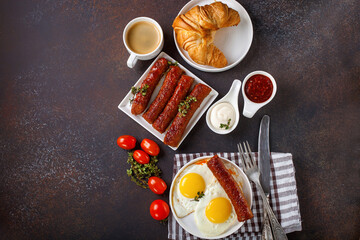 Breakfast - Fried eggs and meat sausages and sauces against a dark background. Selective focus. Copy space. Top view