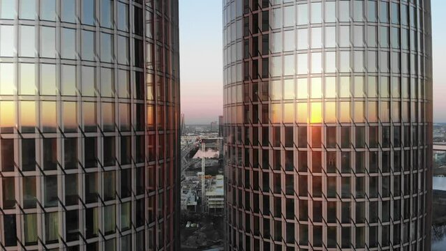 Close up aerial reveal of Zunda glass towers on a sunset with city of Riga in between with clear pink sky in Latvia.