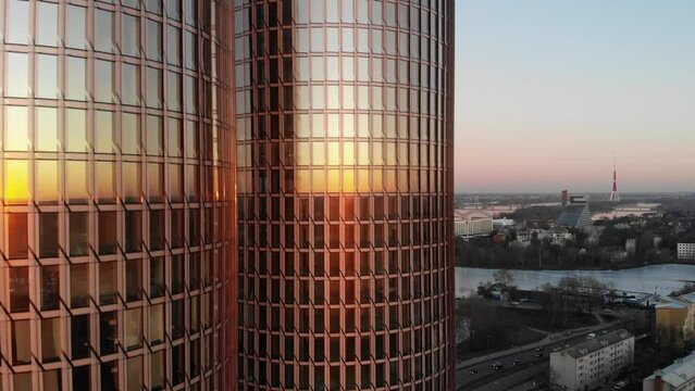 Scenic aerial drone view of Zunda Towers skyscrapers with Riga, Latvia cityscape on right side on a golden sunset evening with clear pink sky