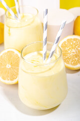 Creamy lemon fruit smoothie, yogurt ar milkshake, Sour sweet drink with fresh lemons on white yellow background copy space