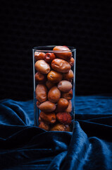 Dried fruits dates in a glass on a dark background with a beautiful light - obrazy, fototapety, plakaty