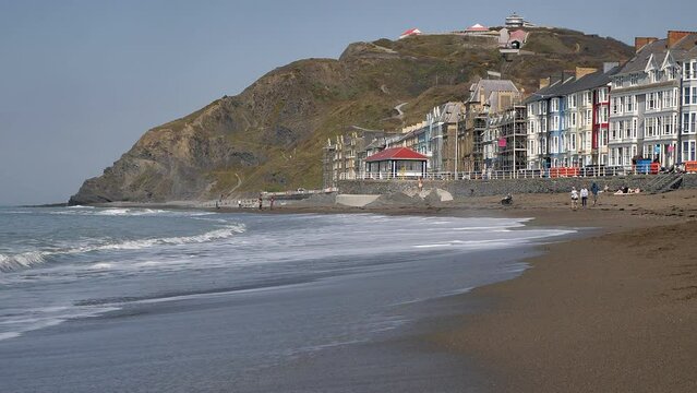 View from sea level of waves on the beach on the Victorian seaside promenade in Aberystwyth, Ceredigion, Wales with the view of the Cliff funicular railway