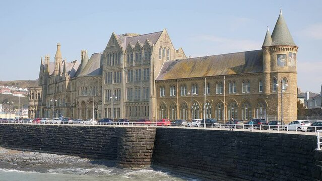 Sea laps at the front of the Old College building on the sea front of Aberystwyth Promenade, Ceredigion, Wales