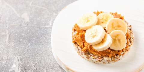 Crisp bread with peanut butter and bananas on a board. Selective focus. Copy space
