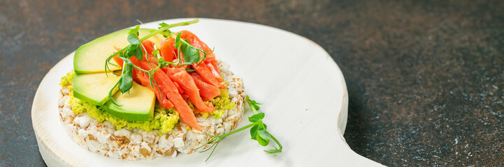 Sandwich with avocado and a salmon against a dark background. Selective focus. Copy space