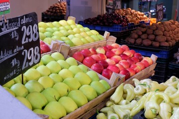different varieties of apples in wooden crates and greenery in a large food market in Budapest, Hungary