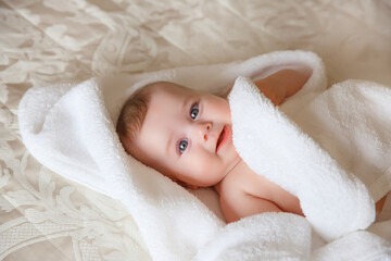 baby is wearing diapers and a white towel in bedroom. top view . A newborn baby is resting in bed after a bath or shower. Children's room. Textiles and bedding for children.