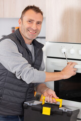 young male repairman repairing oven using digital multimeter