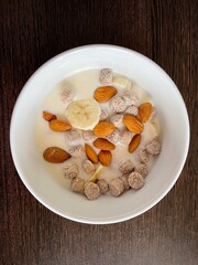 large vertical photo. homemade food. white yogurt with bran and slices of banana with almonds in a round ceramic plate with a pattern. useful vitamin breakfast. eco. bio. diet food.