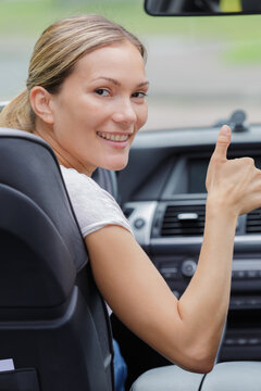 Woman Behind Steering Wheel Showing Thumbs Up