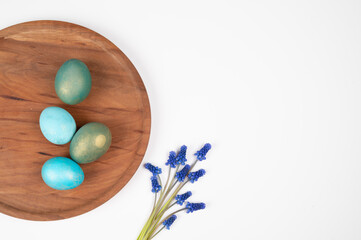 Top view of Easter eggs on wooden plate. Easter greeting card with eggs and flowers isolated on white