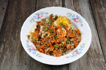 Traditional fired and stirred jasmine rice with mixed vegetable and fresh peeled shrimp serving on the plate. Famous special street food menu in Asia. 