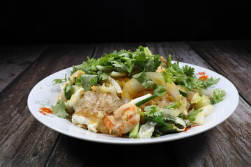 Traditional fried and stirred vermicelli or glass noodle with Chinese celery serving on the plate. Famous street food menu in Asia restaurant.