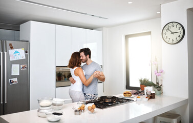 Closer than we ever imagined. Shot of young couple dancing in the kitchen while preparing breakfast.