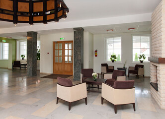 Modern building interior, hotel, reception area, pillars and tiled floor, fireplace and atrium. 