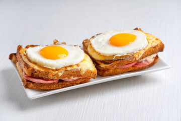 Two homemade Croque Madame French hot sandwiches made with ham and cheese with fried egg on top...