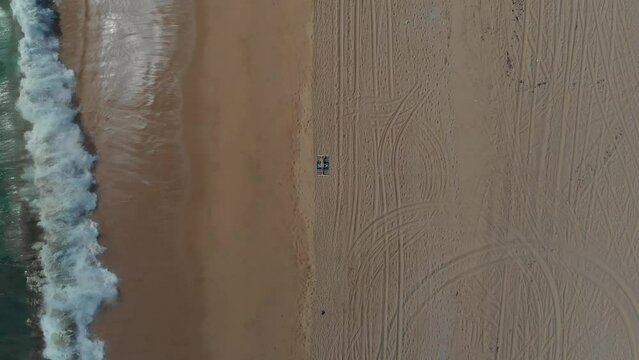 Man on beach in Mexico. Establishing beverage brand shot 4K drone. Slow push in, from high up.