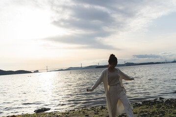 Fototapeta premium 夕暮れの海岸線を歩く女性