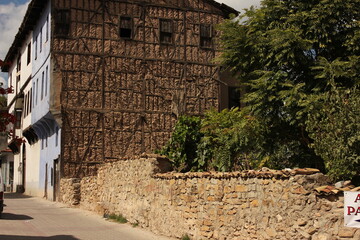 Old vintage masonry village house made of stones, bricks, wood construction. Well preserved early example of Anatolian architecture with stone surrounding garden wall and trees.