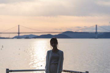 Fototapeta premium 夕暮れの海岸線を歩く女性