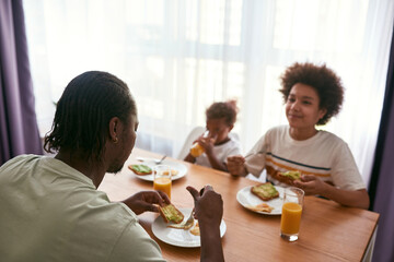 Focus on father eating on blurred son and daughter