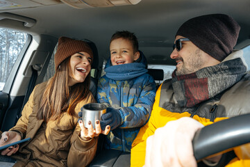 Mother, father and child traveling by car on a vacation to the mountains in winter