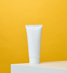 Empty white plastic tubes for cosmetics on a yellow background. Packaging for cream, gel, serum, advertising and product promotion