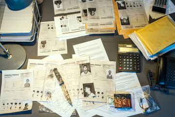 Part of workplace of contemporary fbi agent with criminal profiles, calculators, telephone, packets...
