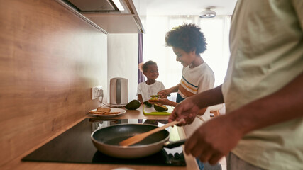 Fototapeta na wymiar Family of father, son and daughter cook breakfast