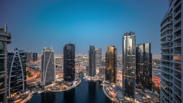 Tall residential buildings at JLT aerial day to night timelapse, part of the Dubai multi commodities centre mixed-use district.