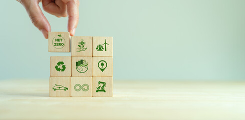 Net zero and carbon neutral concept. Net zero greenhouse gas emissions target. Climate neutral long term strategy.  Putting wooden cubes with green net zero and save world icon on grey backgroud.