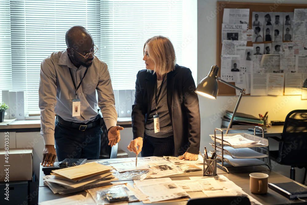 Aufkleber Two interracial agents of FBI discussing criminal profiles at meeting in bureau while one of them pointing at photo of suspect