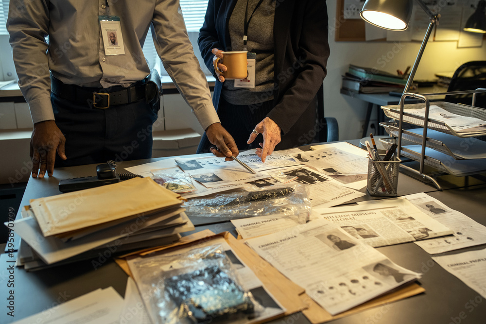 Aufkleber Two interracial agents of FBI pointing at personal information of gang leader while discussing criminal profiles during investigation