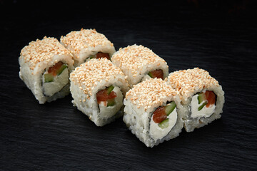Traditional delicious fresh sushi roll set on a black background. Sushi roll with rice, cream cheese, avocado, salmon, sesame. Philadelphia. Sushi menu. Japanese kitchen, restaurant.