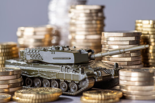 Tank between stacks of coins as a symbol of high armament expenditure