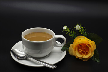 white coffee cup next to the rose on a black background,Include Clipping Path.