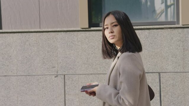 Side view of an adult asian businesswoman walking in the city