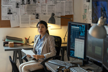 Young serious Hispanic female security department staff with documents looking at camera while...