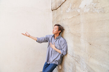 Man dancing posing by textured concrete wall with open hand