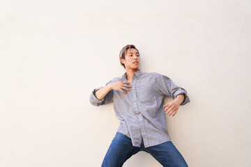 Man dancing by wall with hand to chest