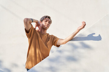 Man posing by white diagonal wall with arm up - obrazy, fototapety, plakaty